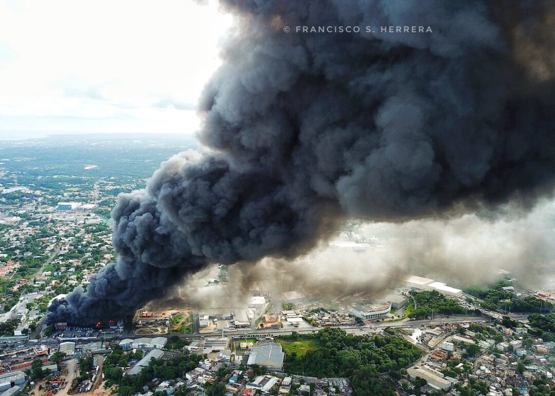 Helicóptero cisterna sobrevuela incendio para mitigar llamas en almacenes #PlazaLama | Vía @LunaValienteRD
